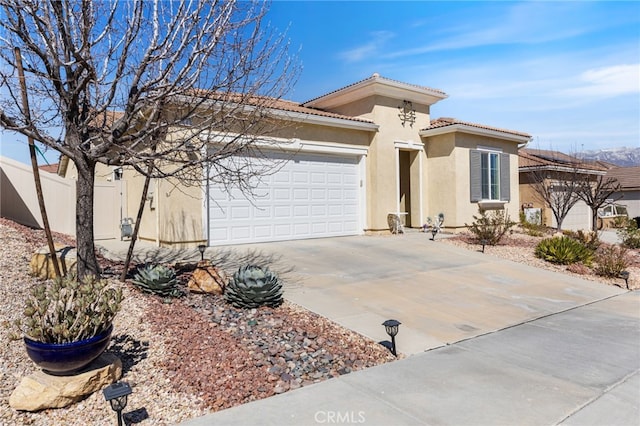 view of front facade with an attached garage, fence, driveway, a tiled roof, and stucco siding