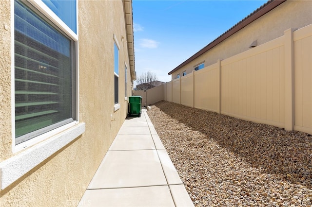 view of side of home featuring a fenced backyard and stucco siding