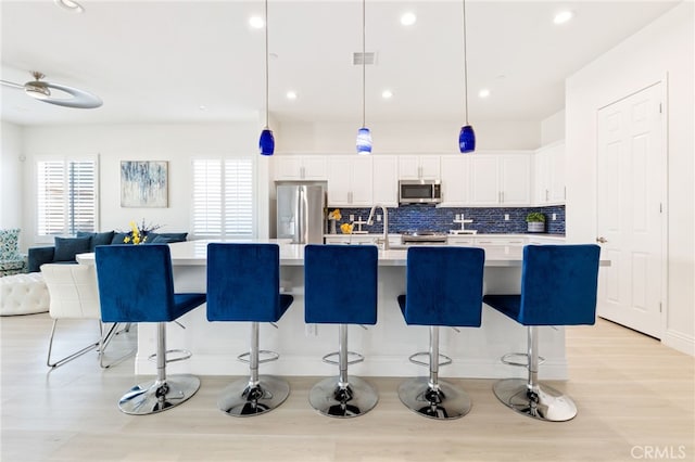 kitchen featuring white cabinets, tasteful backsplash, appliances with stainless steel finishes, and light countertops