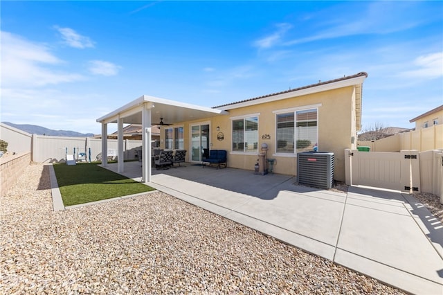 back of house featuring stucco siding, a fenced backyard, a gate, and central air condition unit