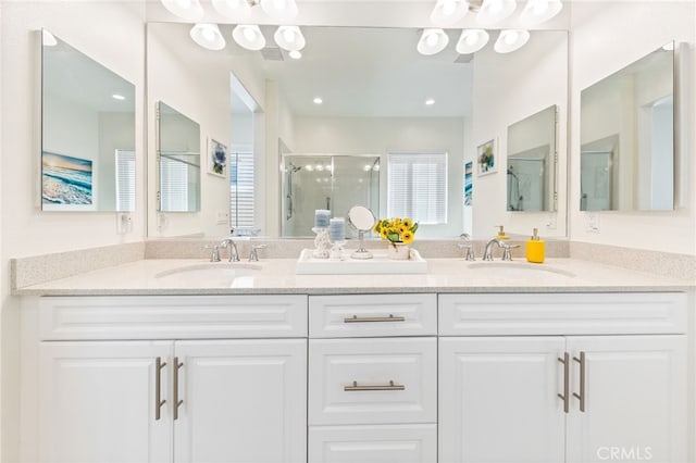 full bath with double vanity, a sink, and a shower stall