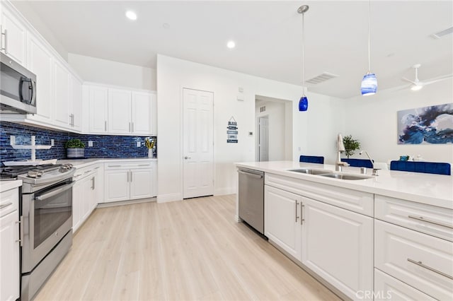 kitchen with light wood finished floors, stainless steel appliances, tasteful backsplash, light countertops, and white cabinetry