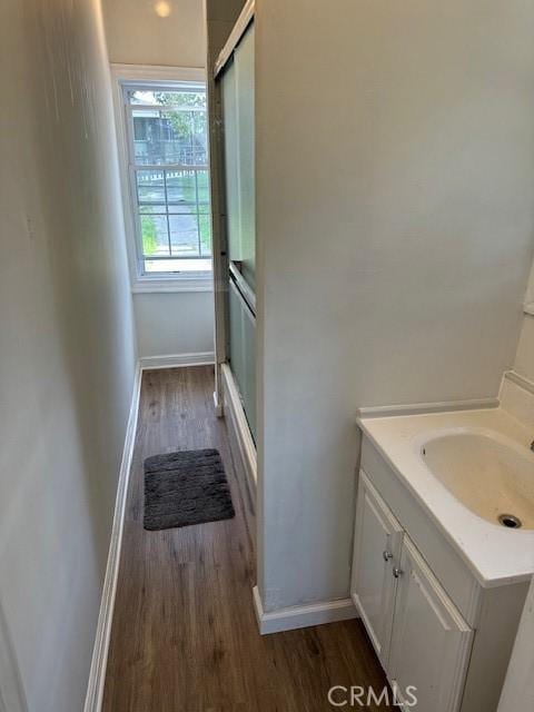 bathroom with wood finished floors, an enclosed shower, vanity, and baseboards