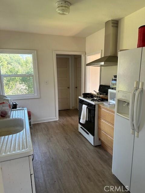 kitchen featuring wood finished floors, white appliances, light countertops, and extractor fan