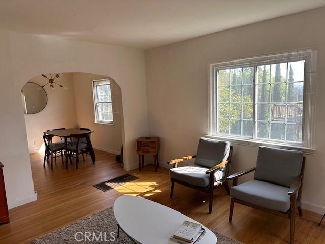 living area with arched walkways, wood finished floors, and baseboards