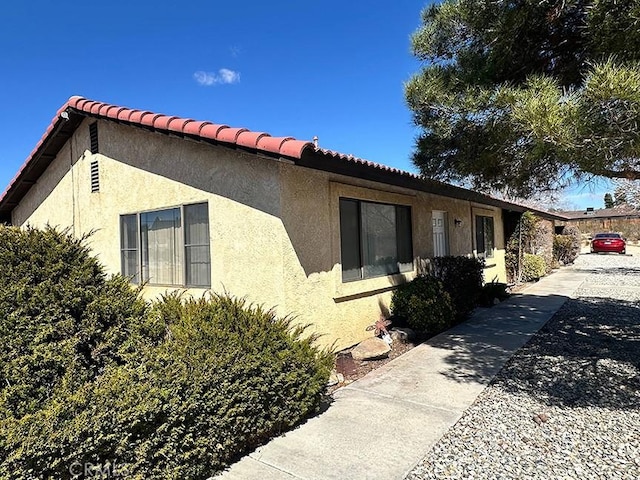 view of property exterior with stucco siding and a tile roof