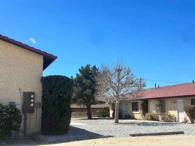 view of side of property featuring a tile roof and stucco siding