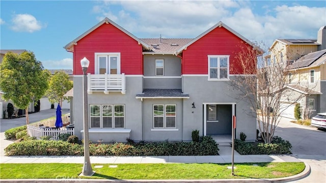 multi unit property with a balcony, driveway, a shingled roof, and stucco siding