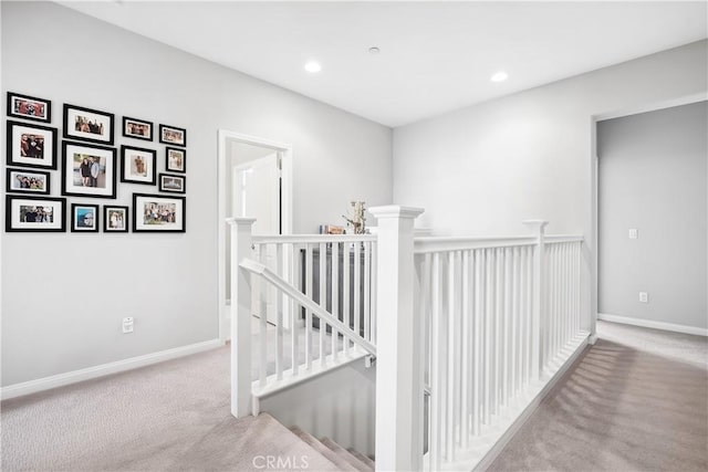 corridor with carpet floors, recessed lighting, baseboards, and an upstairs landing