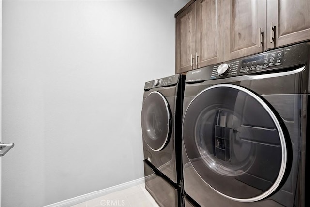 washroom featuring cabinet space, washer and clothes dryer, baseboards, and light tile patterned floors