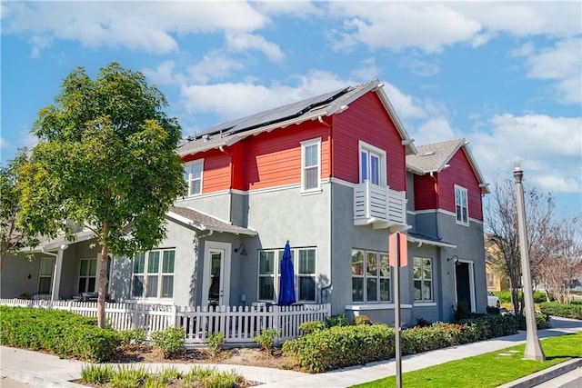 view of home's exterior with a fenced front yard, stucco siding, and solar panels