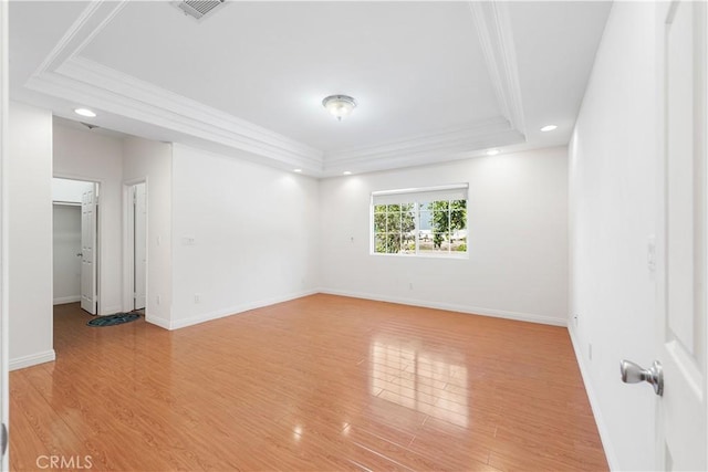 spare room featuring light wood-style floors, visible vents, ornamental molding, and baseboards