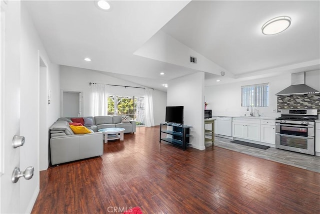 living area featuring lofted ceiling, a healthy amount of sunlight, recessed lighting, and wood finished floors