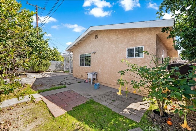 back of property with a patio area, fence, and stucco siding