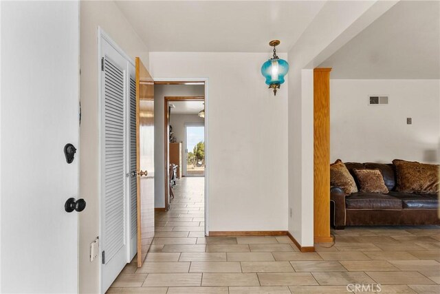 hall featuring visible vents, baseboards, and wood tiled floor