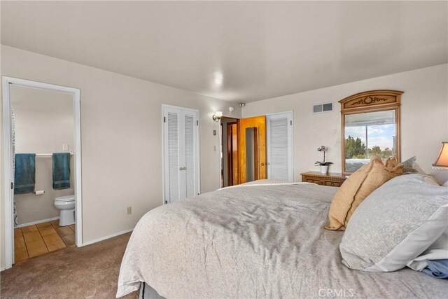 carpeted bedroom featuring visible vents, baseboards, and connected bathroom