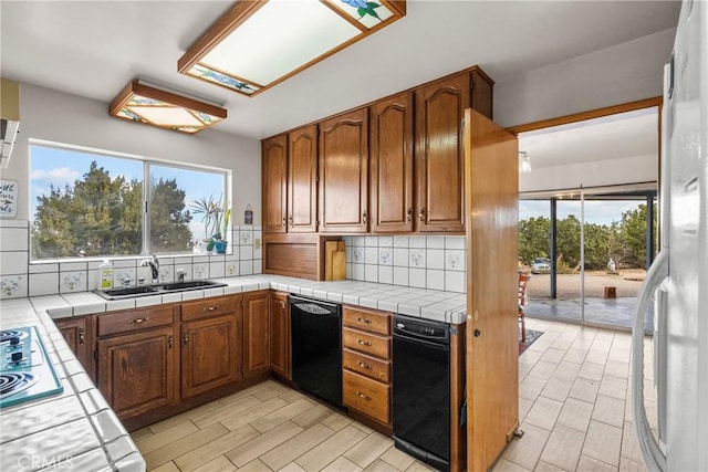 kitchen featuring decorative backsplash, tile countertops, black dishwasher, and a sink