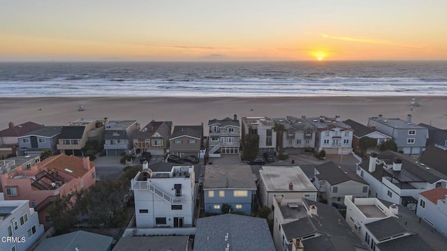 drone / aerial view featuring a water view, a residential view, and a beach view