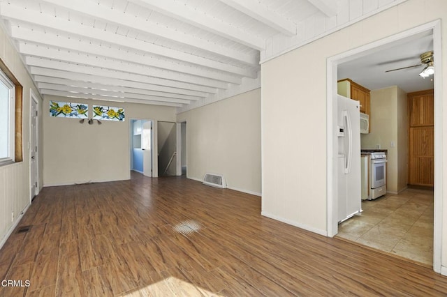 spare room with ceiling fan, wood finished floors, visible vents, a healthy amount of sunlight, and beam ceiling