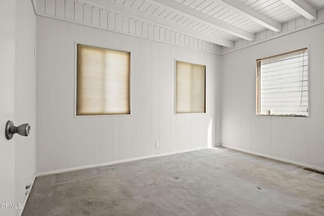 carpeted empty room with beamed ceiling, visible vents, and baseboards