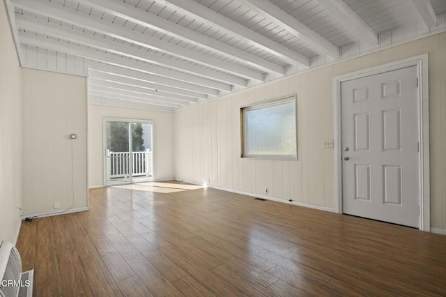 empty room featuring beam ceiling and wood finished floors