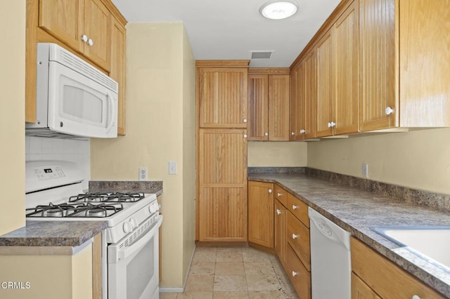 kitchen with dark countertops, white appliances, and visible vents