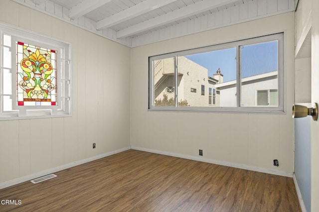 unfurnished room featuring visible vents, plenty of natural light, beamed ceiling, and wood finished floors