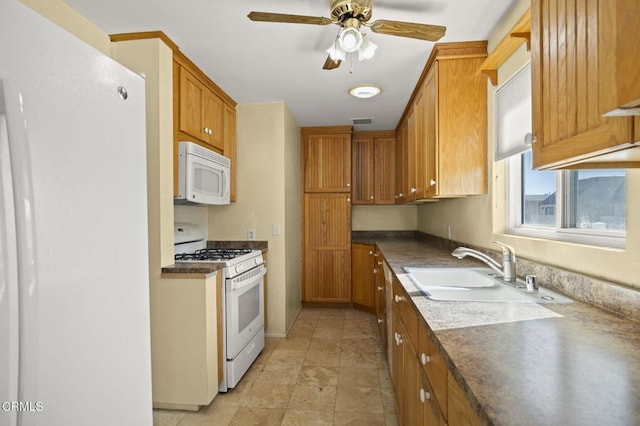 kitchen with white appliances, visible vents, brown cabinetry, dark countertops, and a sink