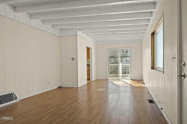 unfurnished room featuring beamed ceiling, wood finished floors, visible vents, and baseboards