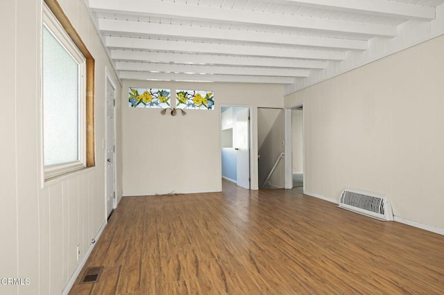 spare room with beam ceiling, wood finished floors, visible vents, and baseboards