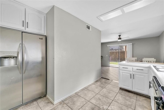 kitchen featuring light tile patterned flooring, stainless steel fridge, visible vents, and white cabinets