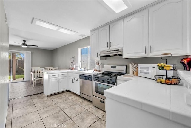 kitchen with stainless steel appliances, a sink, a peninsula, plenty of natural light, and under cabinet range hood