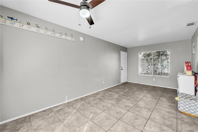 empty room with ceiling fan, tile patterned flooring, visible vents, and baseboards