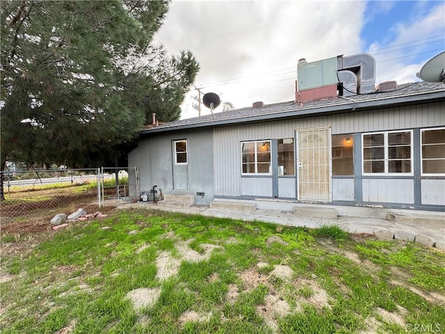 back of house featuring entry steps, fence, and a lawn