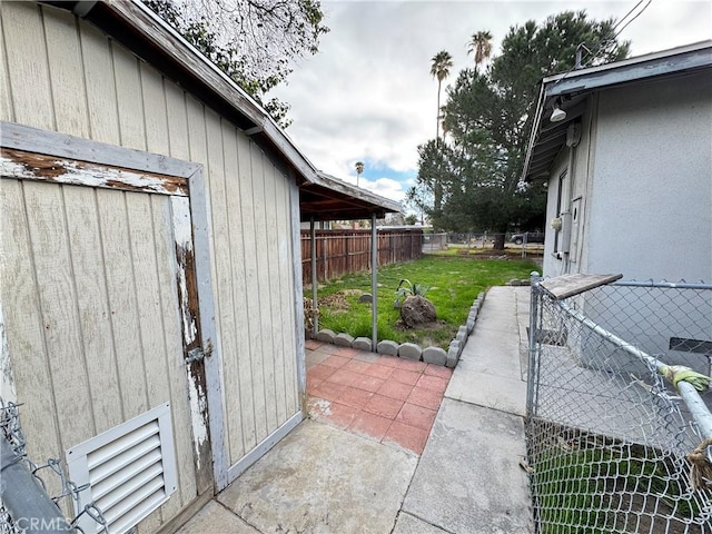 view of side of home featuring fence, a lawn, and a patio