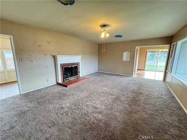 unfurnished living room with lofted ceiling, carpet floors, a brick fireplace, and baseboards