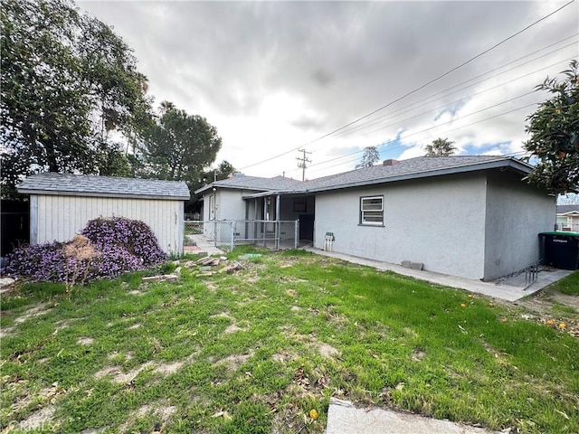 back of house featuring a lawn, fence, and stucco siding