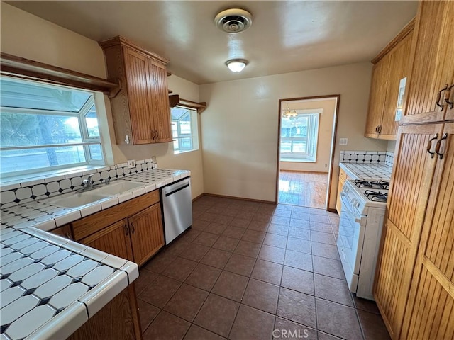 kitchen with gas range gas stove, tile counters, visible vents, a sink, and dishwasher