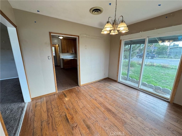 empty room with light wood finished floors, visible vents, baseboards, and a notable chandelier