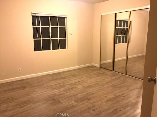 unfurnished bedroom featuring a closet, baseboards, and wood finished floors