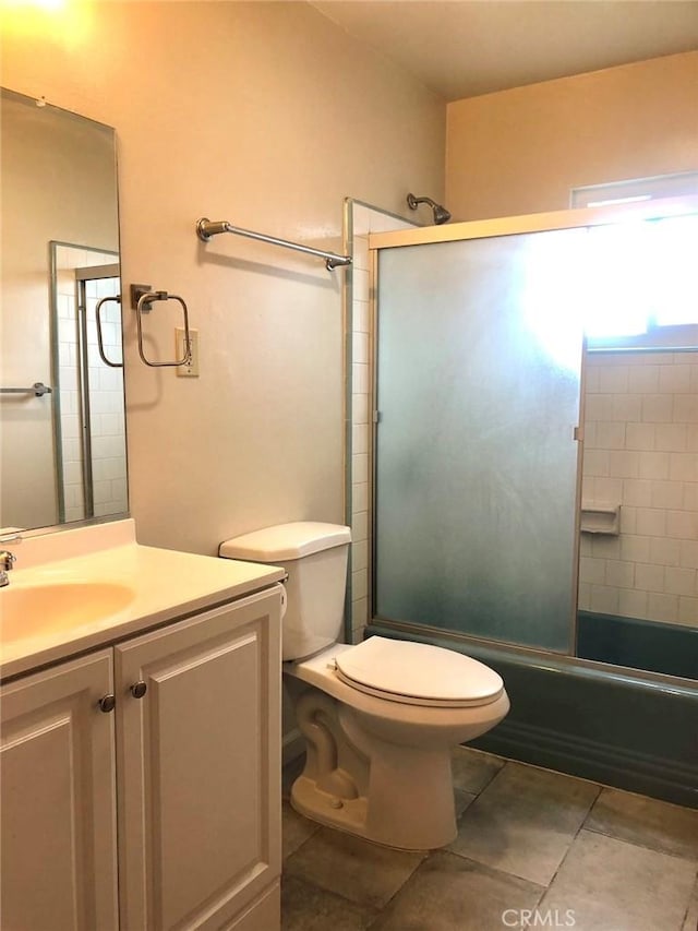 full bath with shower / bath combination with glass door, vanity, toilet, and tile patterned floors