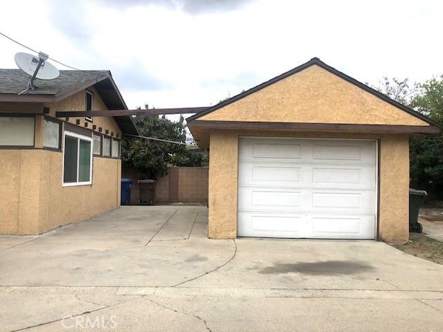 detached garage with concrete driveway and fence