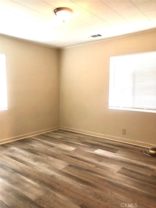 unfurnished room with baseboards, visible vents, and wood finished floors