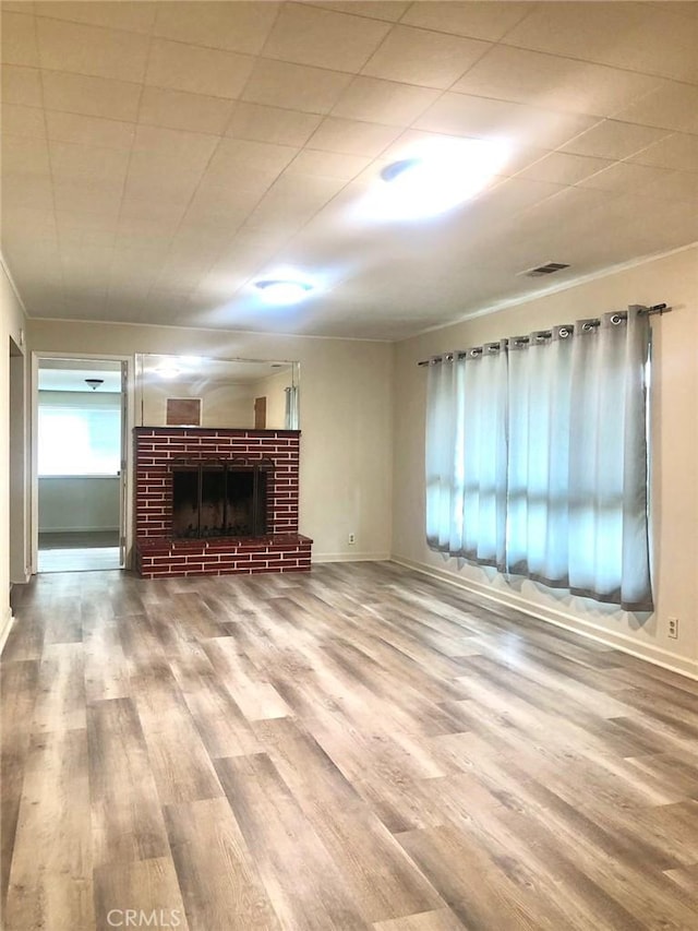 unfurnished living room with a wealth of natural light, a fireplace, visible vents, and wood finished floors