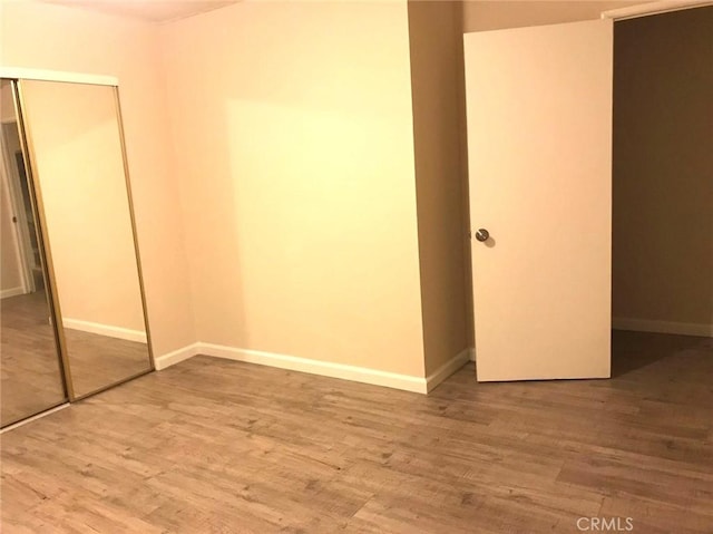 unfurnished bedroom with a closet, baseboards, and wood finished floors