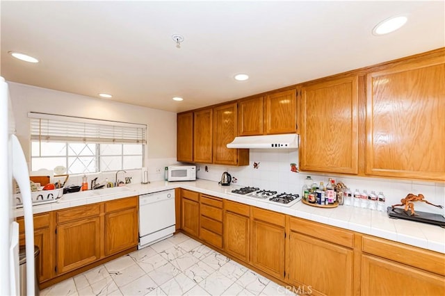 kitchen with brown cabinets, white appliances, under cabinet range hood, and decorative backsplash