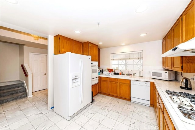 kitchen featuring white appliances, marble finish floor, brown cabinetry, and a warming drawer