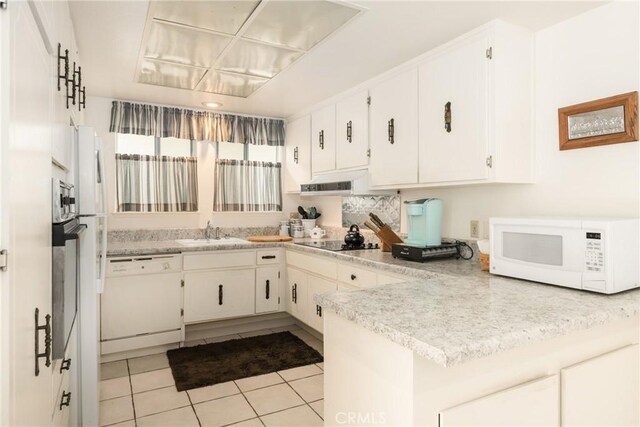 kitchen with light tile patterned floors, light countertops, a sink, white appliances, and a peninsula