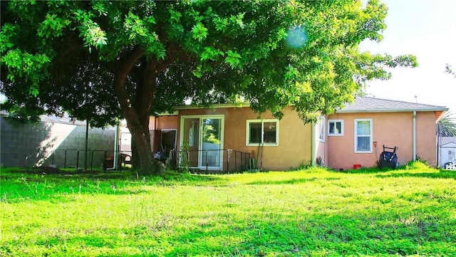 back of property with stucco siding, fence, and a yard