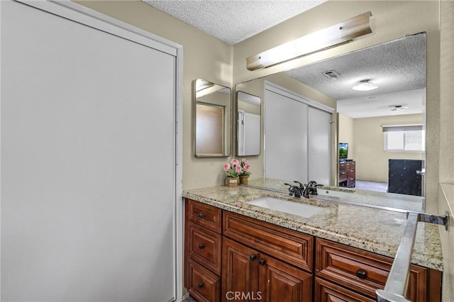 bathroom featuring a textured ceiling, vanity, and visible vents